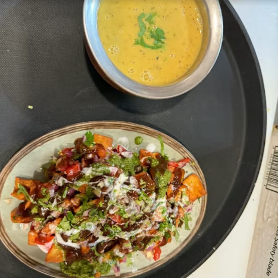 A plate of loaded sweet potato fries with sauces and a bowl of yellow lentil soup.
